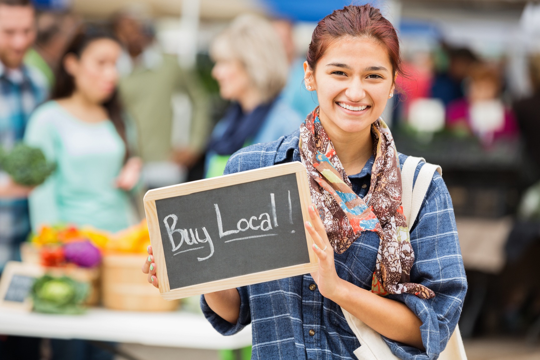 Pretty woman holding Buy Local sign at local farmers market